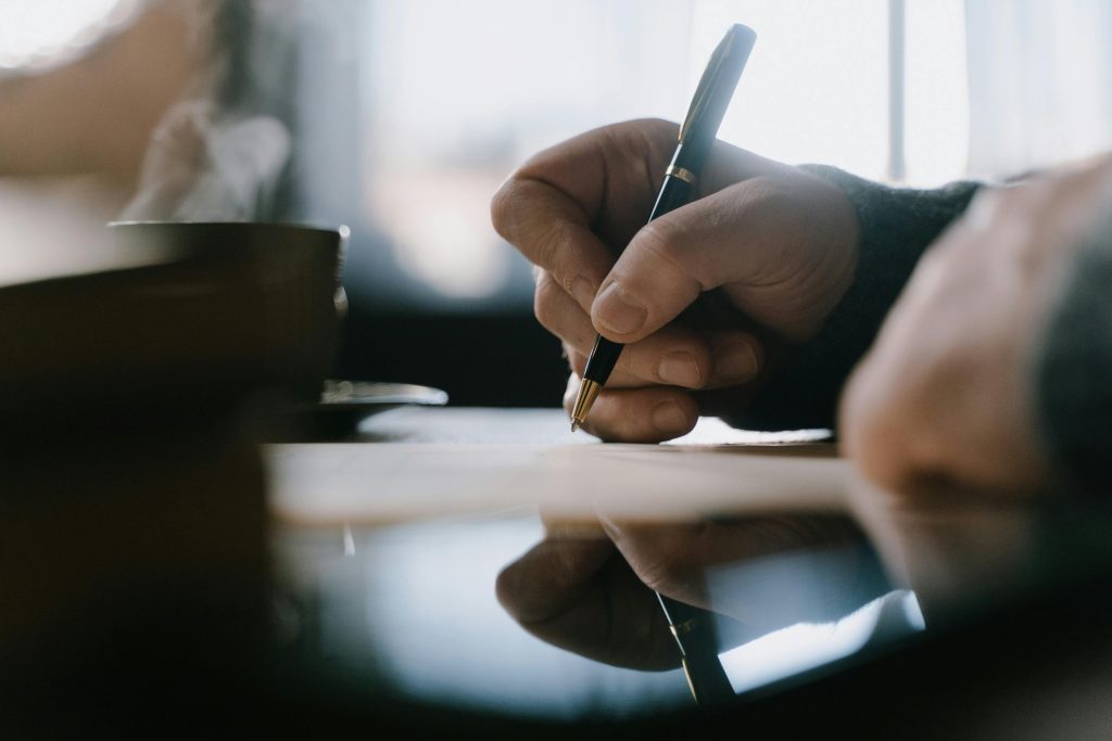 A hand holding a pen and filling in a form